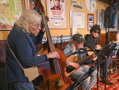 Three musicians in a row inside an Irish pub.