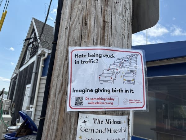 A sign posted outside with an illustration of car traffic. It reads "Hate being stuck in traffic? Imagine giving birth in it"