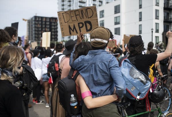 Demonstrators hold a sign. 