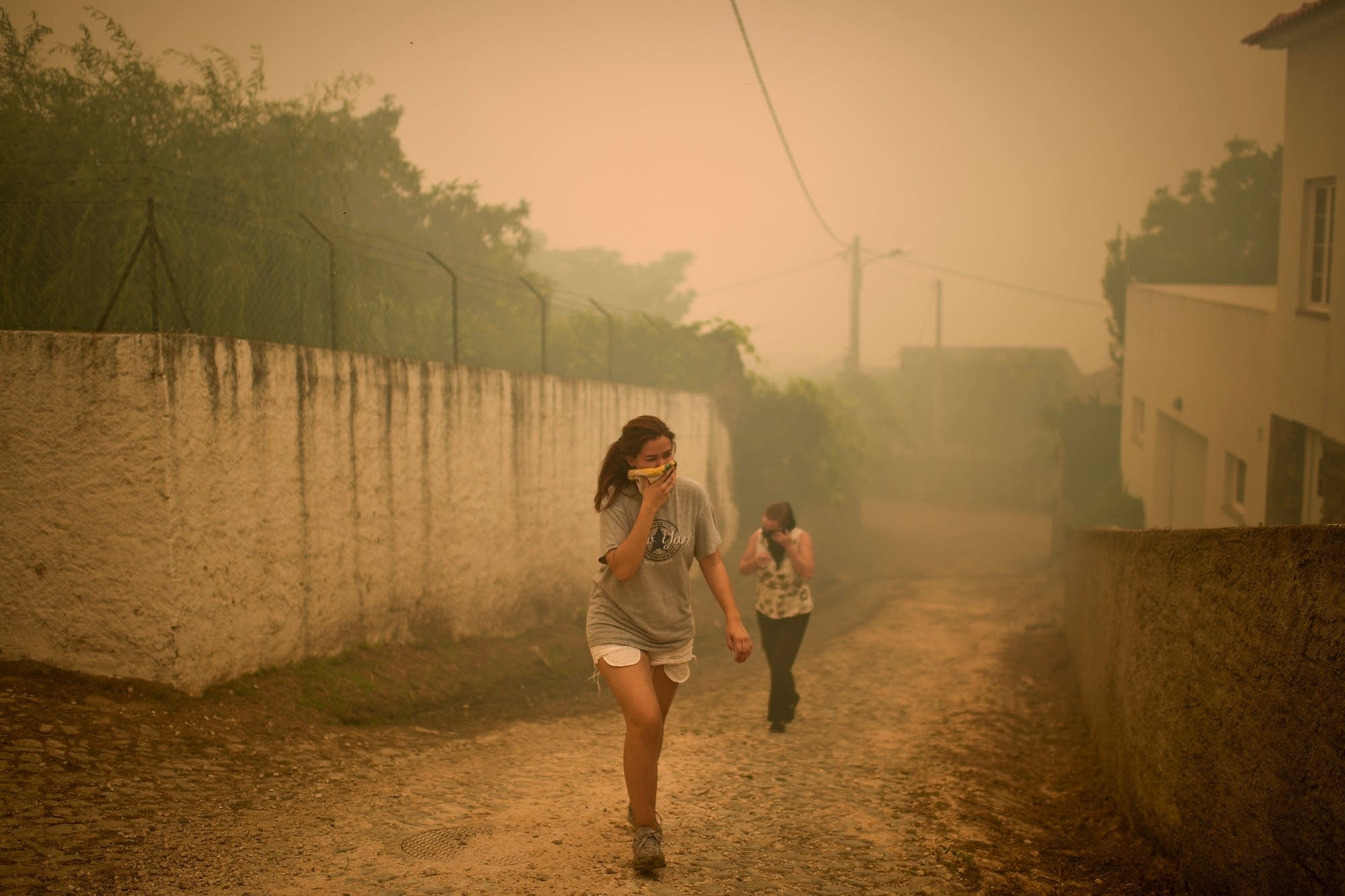 Two persons cover their mouths and noses with a tissue during a wildfire.