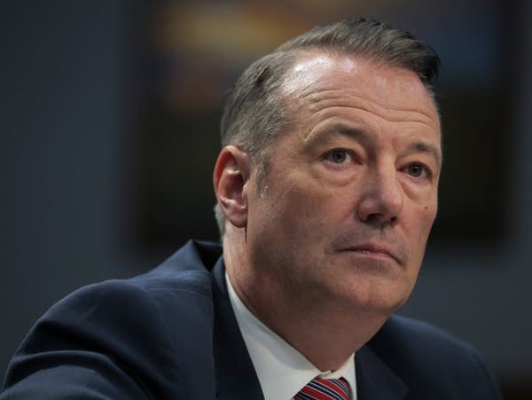 A man in a suit listens to a question