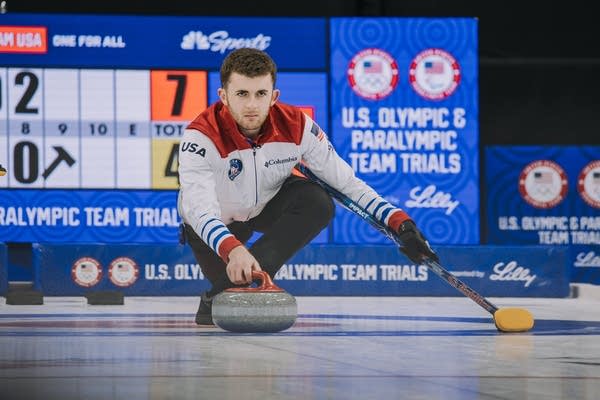 A man leans down to throw a curling stone.