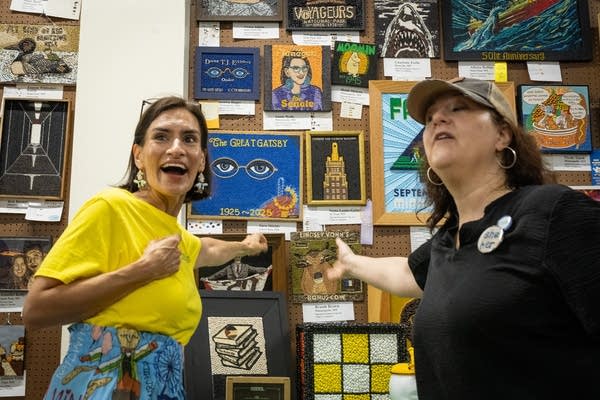 Two women stand next to crop art