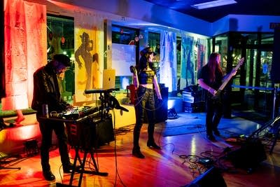 Three musicians perform onstage in a nontraditional music venue