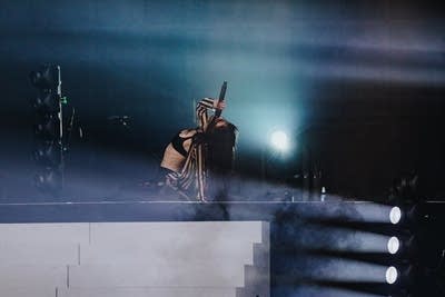 A musician sings on a large outdoor stage