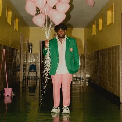 A man holding a bouquet of balloons, standing in a hallway