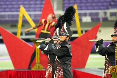 A marching band performs on the field of a football stadium.