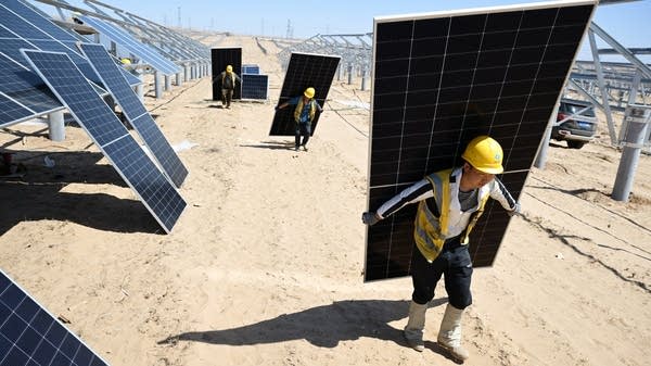 Above, workers carry solar panels to be installed in the desert in China's northern Ningxia region in April 2025.