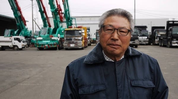 Smile Smile Taxi owner Matsuo Sato stands in front of his new fleet of dump trucks and heavy construction machinery. Sato invested in these vehicles to capitalize on the rebuilding of the region.