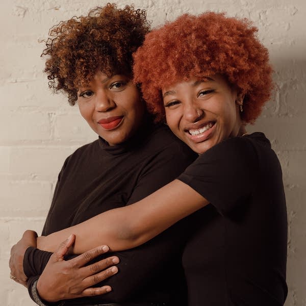 Two women stand and hug
