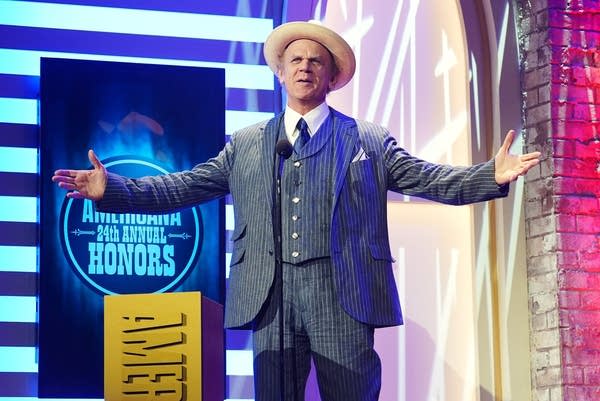 A man in a suit addresses an audience