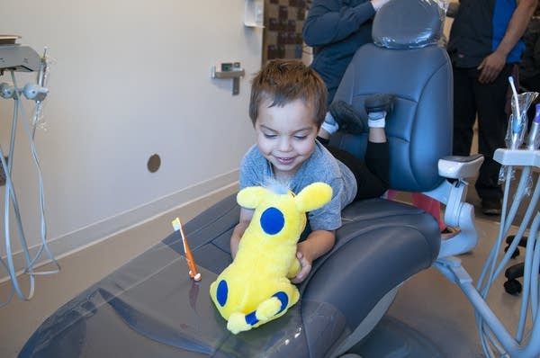 A child plays with a toy while in a dentist's chair. 