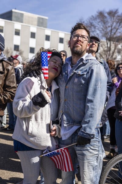 Two people stand together at a protest