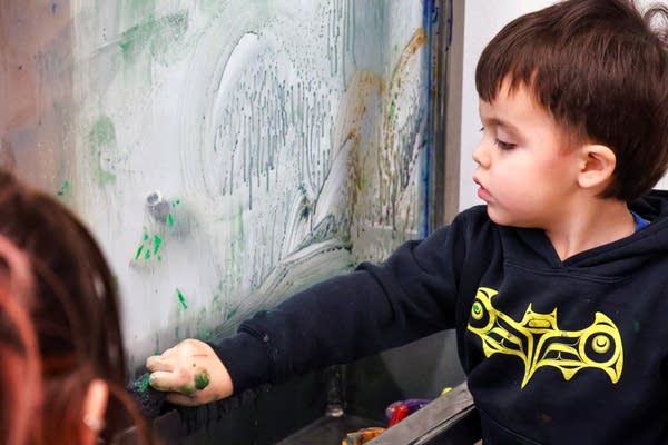 A child paints on a see-through wall.