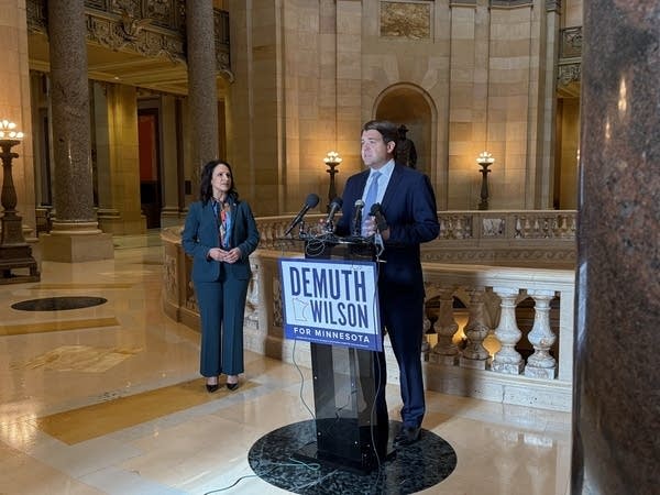 Two people give a press conference at a podium reading "Demuth Wilson for Minnesota" in the Capitol rotunda.