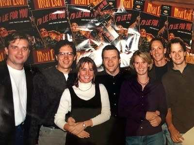 Seven people gathered for a photo at a concert venue