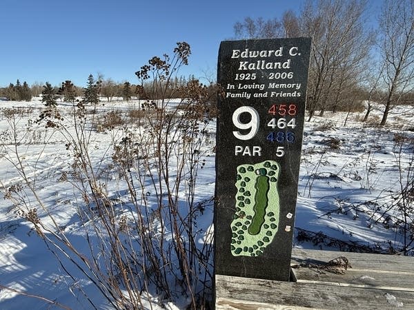 A sign for the 9 hole, covered in snow, at a closed golf course.