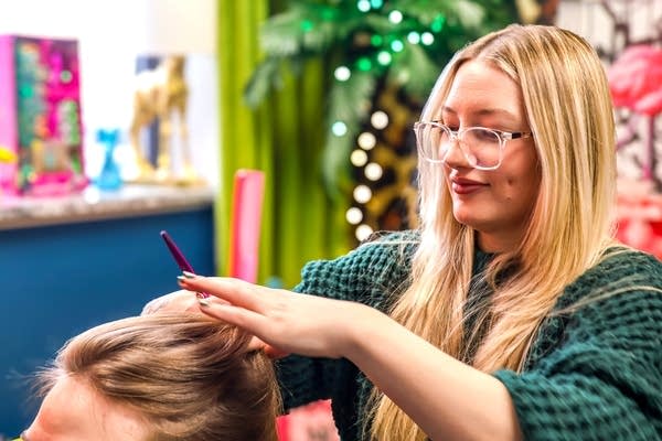 A stylist cuts a client's hair with scissors.