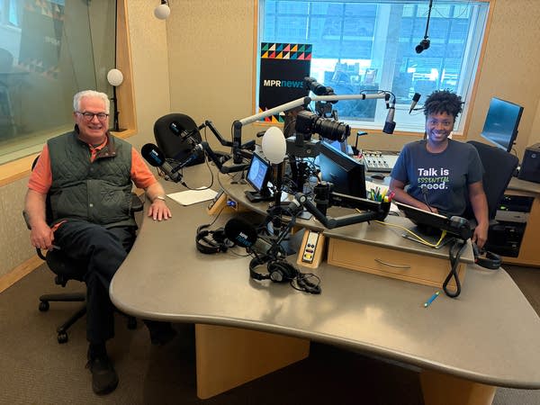 two people smiling in a broadcast studio