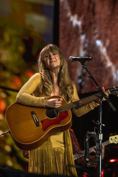 A woman sings and plays guitar onstage