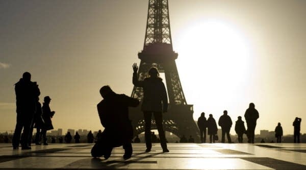 Tourists pose at the Trocadero square with the Eiffel tower in the background at sunrise in Paris.