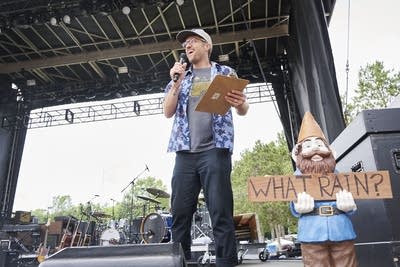A man smiles and speaks into a microphone onstage