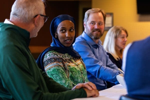 People smile and talk while sitting at a table.