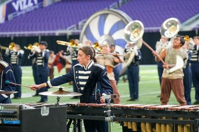 A marching band performs on the field of a football stadium.