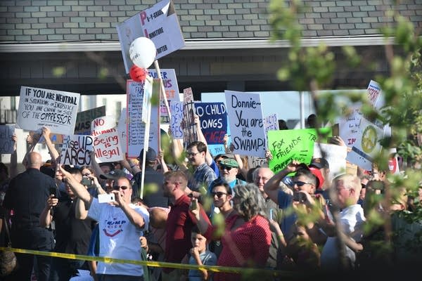 Protesters line the President Trump's motorcade route near Scheels Arena.