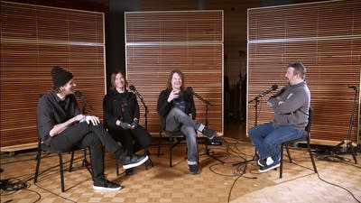 Four men having a conversation in a recording studio