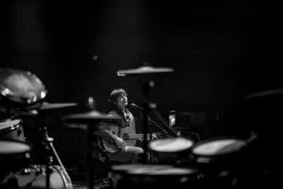 A musician sings and plays guitar onstage in a music club