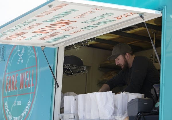 A man packs bags of lunch inside a food truck.