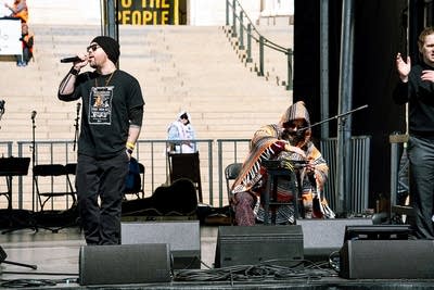 A hip-hop duo performing on an outdoor stage at a large rally