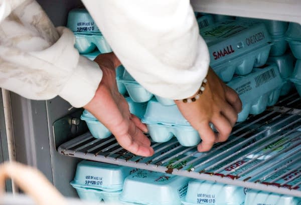 A person puts away cartons of eggs.