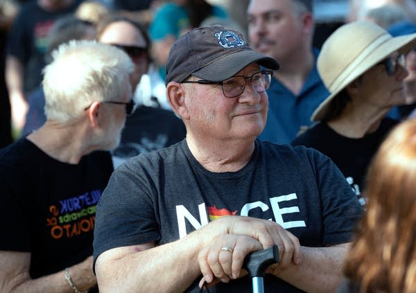 Man in shirt and hat listens to speakers