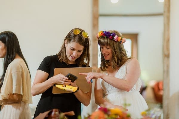 woman with clipboard stands next to women in bridal dress