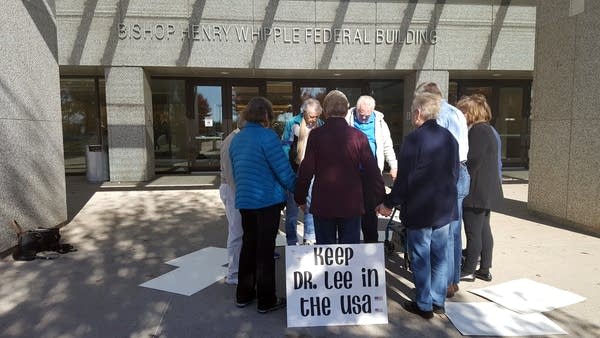 Supporters of Dr. Guan Lee pray in front of a federal building.