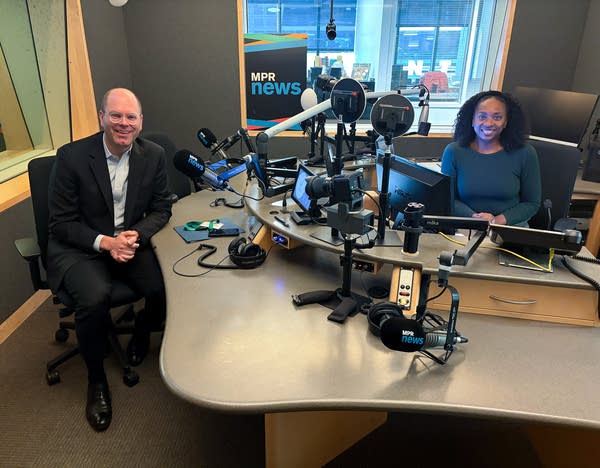 two people smiling in a broadcast studio