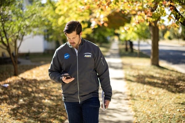 A man checks his phone while walking down a sidewalk