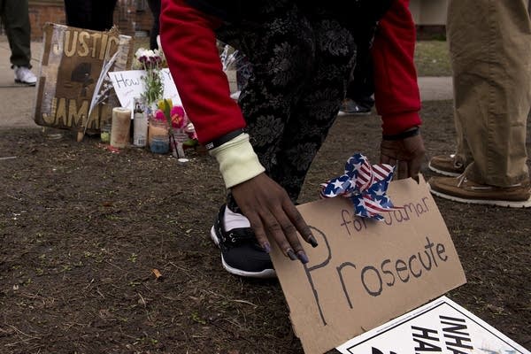 Jamar Clark's sister Joyce Powell sets a up sign.