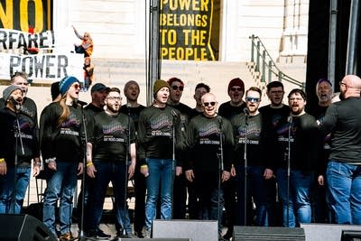 A choir singing on an outdoor stage at a large rally