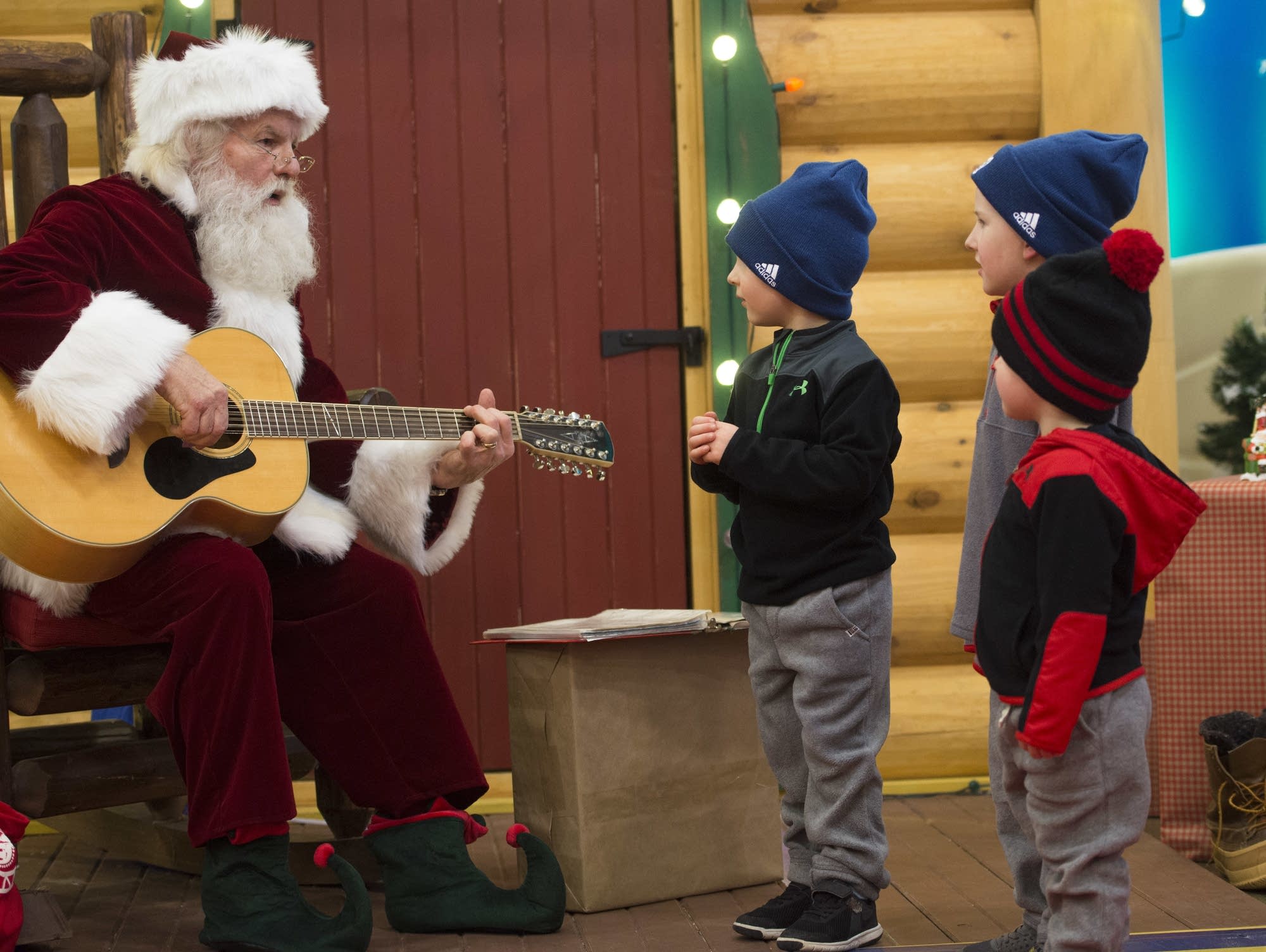 Kurt Martell plays Jingle Bells on guitar as three brothers sing along.