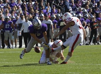 A football player wearing a purple jersey blocks a kick.