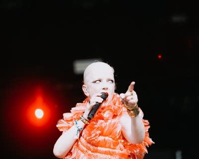 A woman sings and gestures on a large outdoor stage