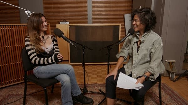 Two people have a conversation in a recording studio