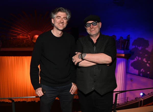 Two men stand in front of a historic movie palace
