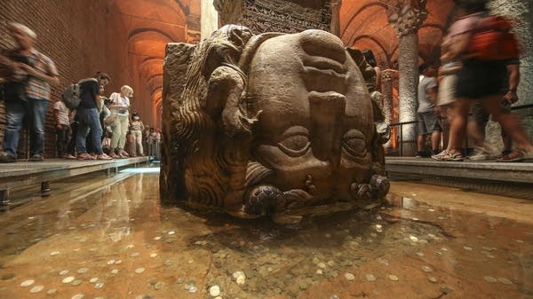 Visitors walk past a Medusa based column 