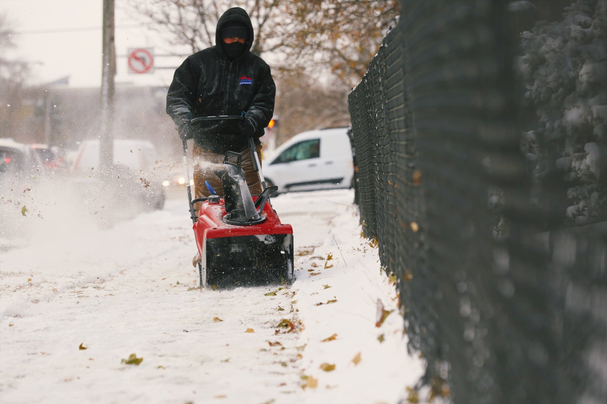A man clears snow, ice and leaves from the sidewalk in Minneapolis.