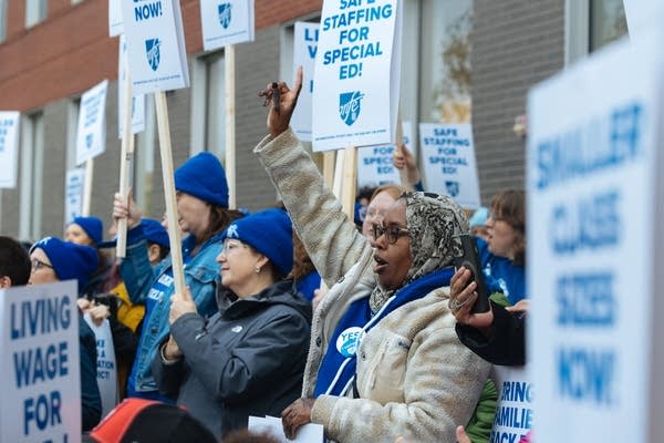 Demonstrators chant while holding picket signs.