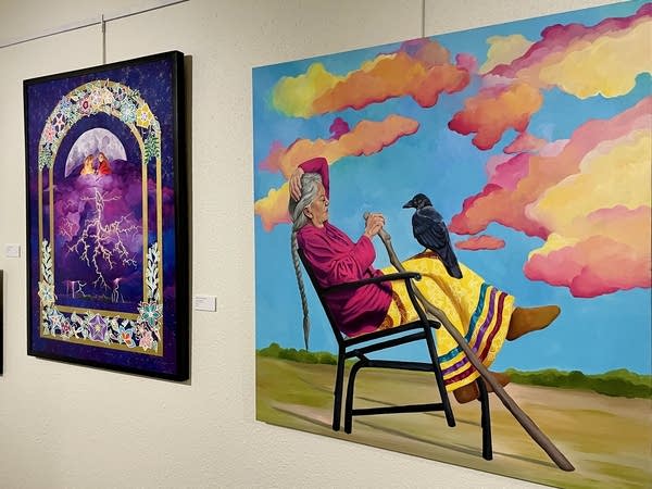 Brightly colored paintings hang on a gallery wall.